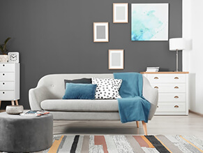 Modern_Grey_Living_Room_blue_cushions_grey_couch_white_drawes_lamp_coloured_rug_floorboards 